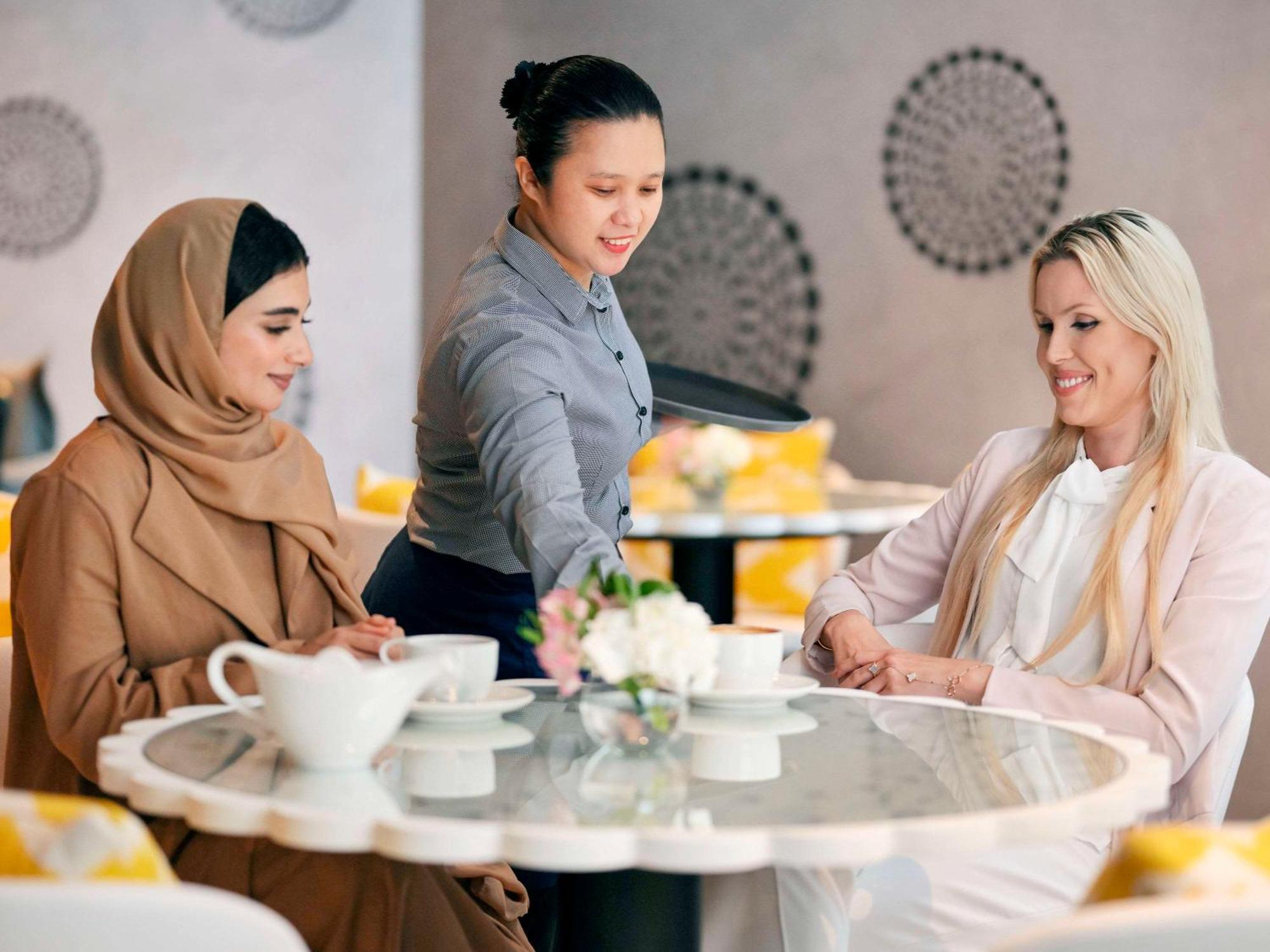 Moevenpick Hotel & Apartments Ghala Muscat Exteriör bild A waitress serving customers